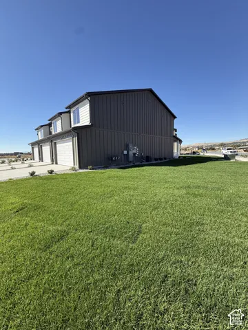 Exterior featuring vertical panel siding, multiple garage bays, and upper-level windows