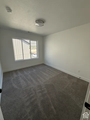 Recessed ceiling light, neutral wall paint, white trim, gray patterned carpeting, and a window with mountain scenery