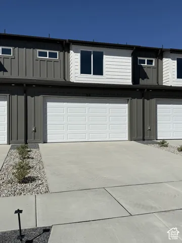 Two-story townhome with a two-car garage, concrete driveway, and board and batten siding