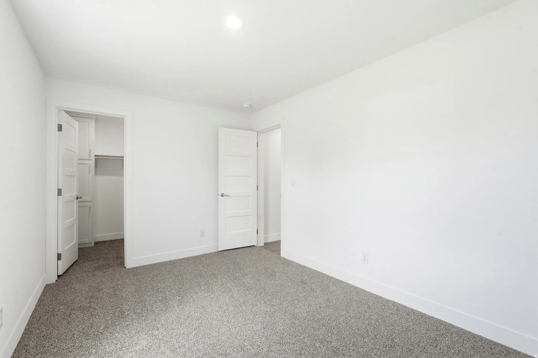 Spacious interior room with light grey carpeting, white painted walls, and white trim