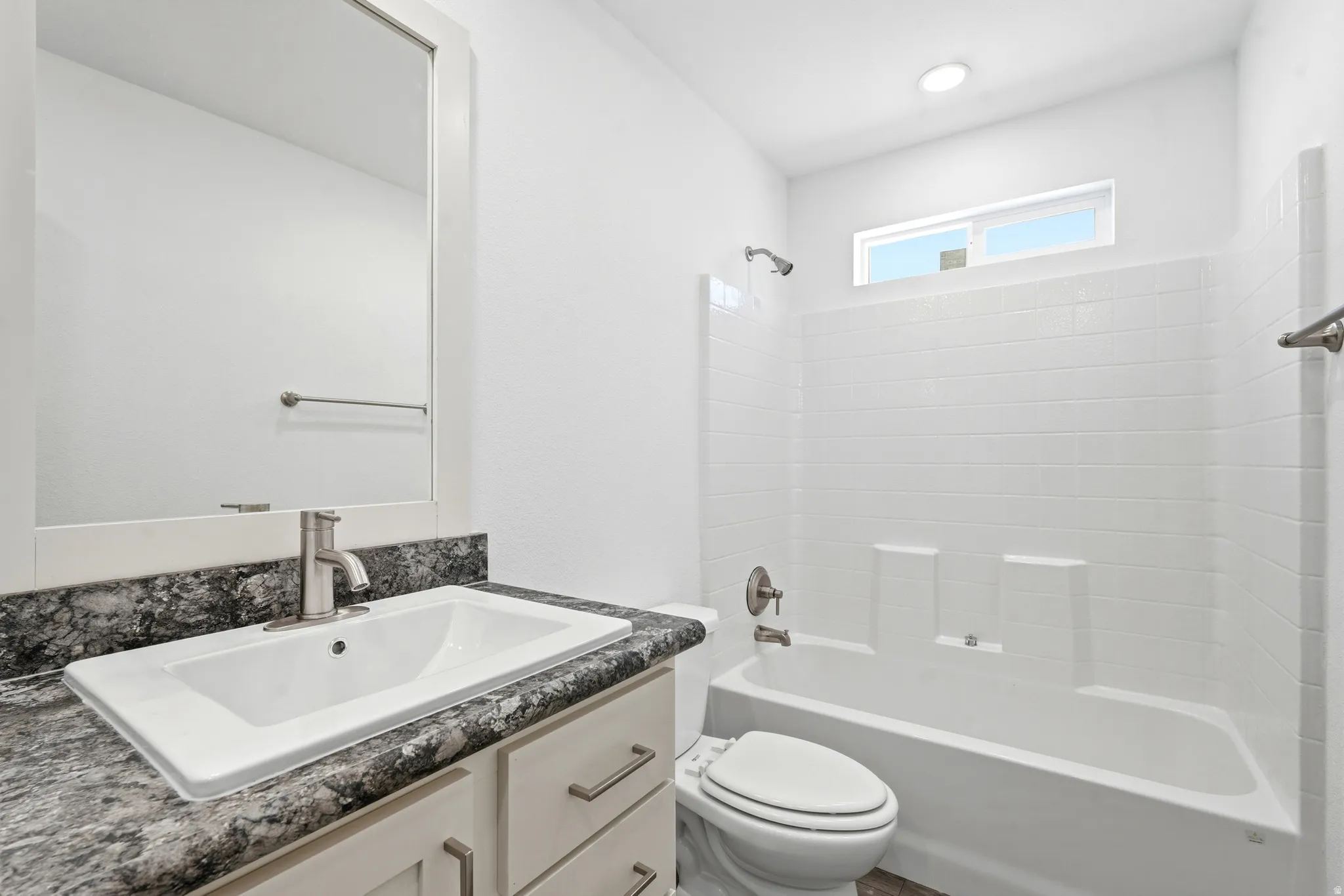Bathroom featuring a single vanity with a patterned countertop, a rectangular undermount sink, and brushed nickel fixtures