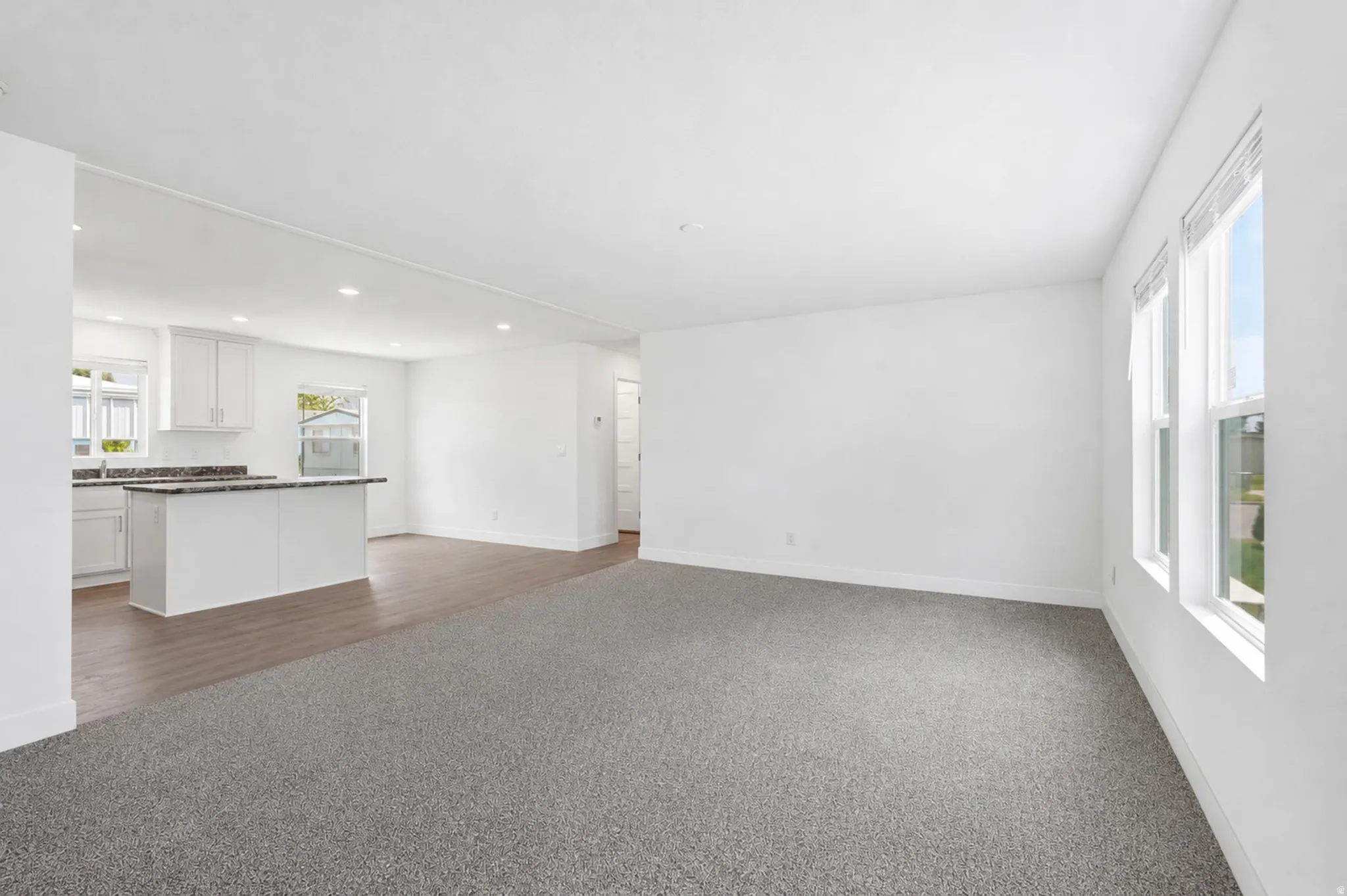 Spacious living area featuring neutral carpeting and multiple windows