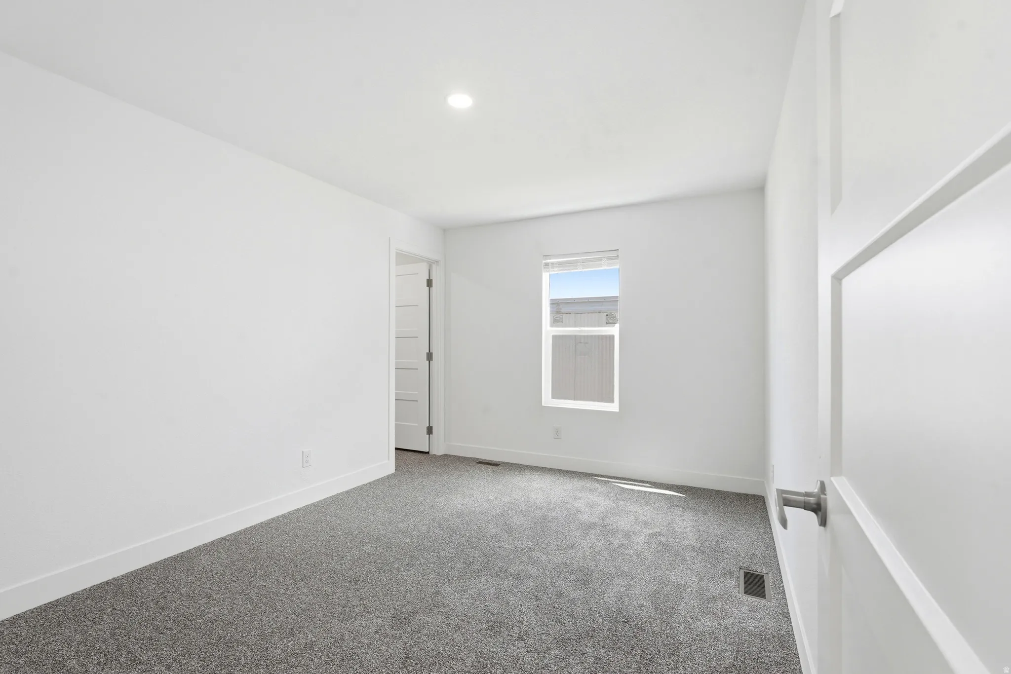 Bedroom featuring light gray carpeting, white walls, a recessed ceiling light, and a single window