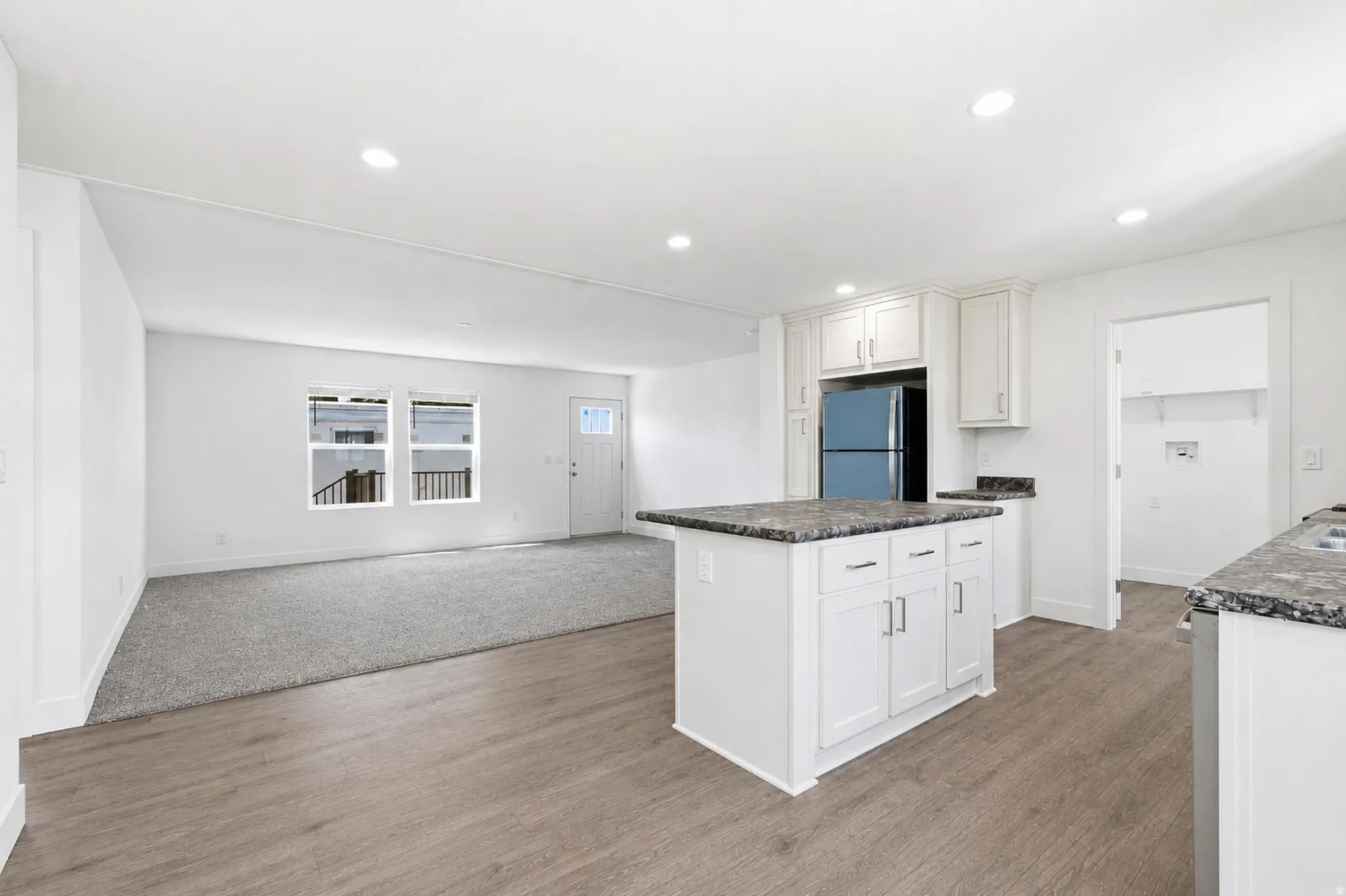 Open-concept living space featuring wood-finish flooring, recessed lighting, and a kitchen island with stone countertops