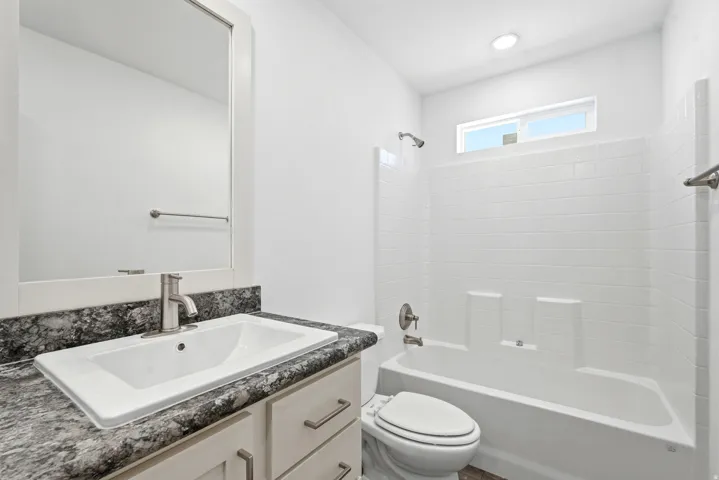 Bathroom featuring a single vanity with a patterned countertop, a rectangular undermount sink, and brushed nickel fixtures