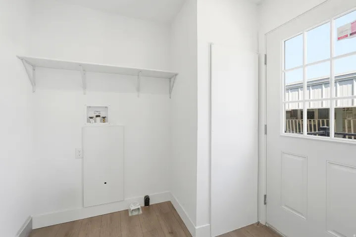 Utility area featuring wood-finish flooring, white walls, and a windowed exterior door