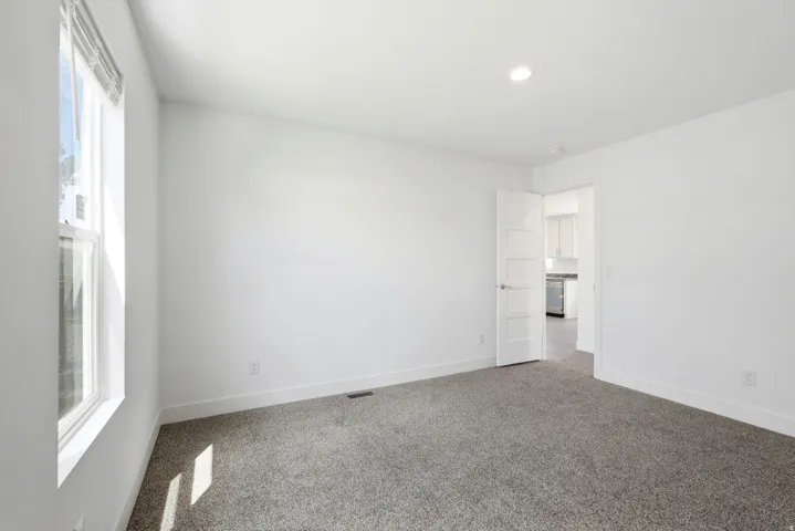 Carpeted room with white walls, recessed lighting, and a single window