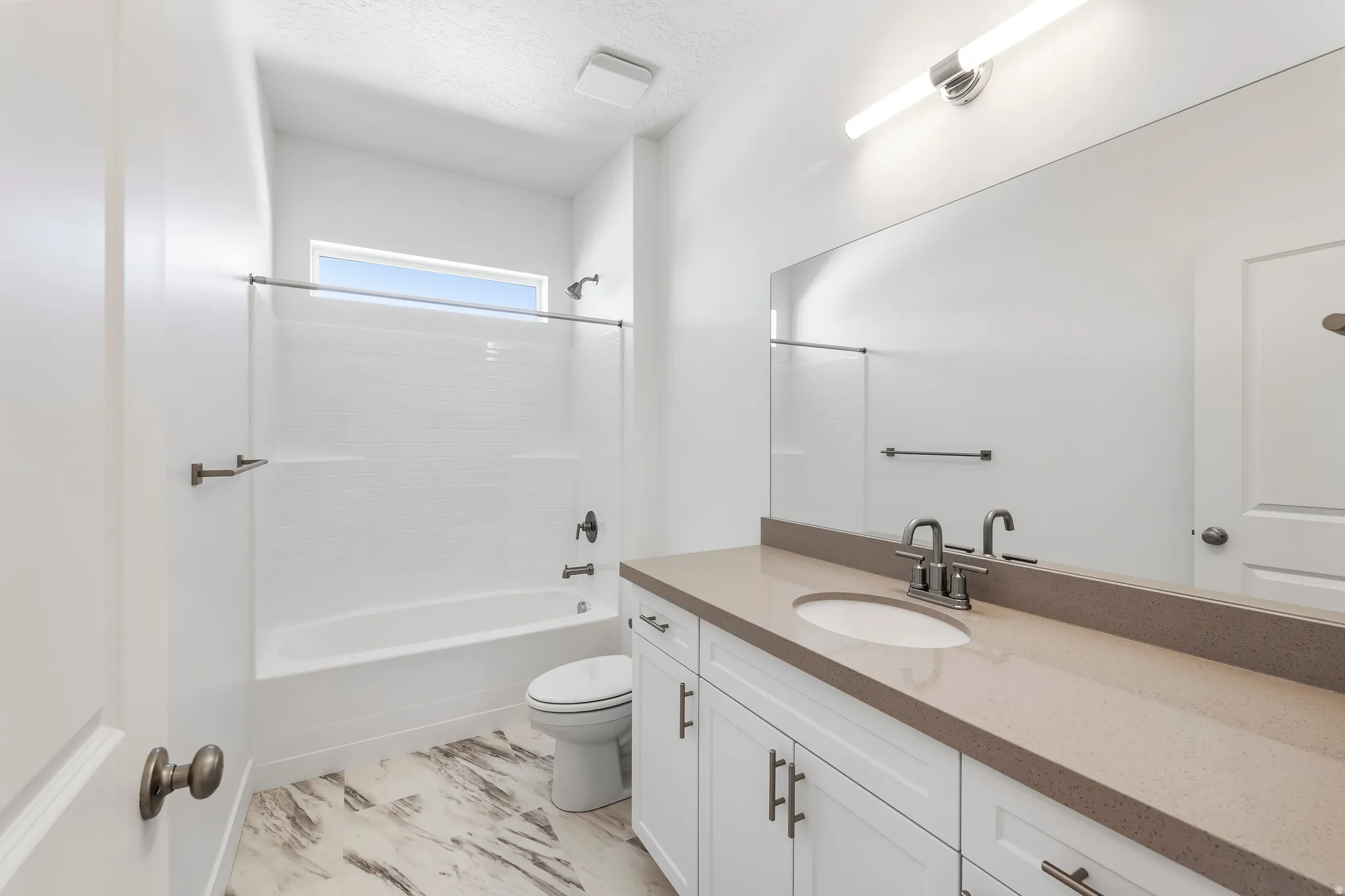 Modern bathroom featuring a single vanity with a light gray countertop, undermount sink, and brushed nickel faucet
