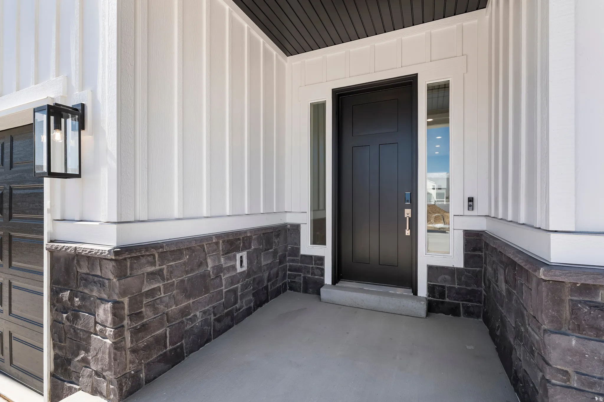 Contemporary exterior featuring white vertical siding and dark stone veneer