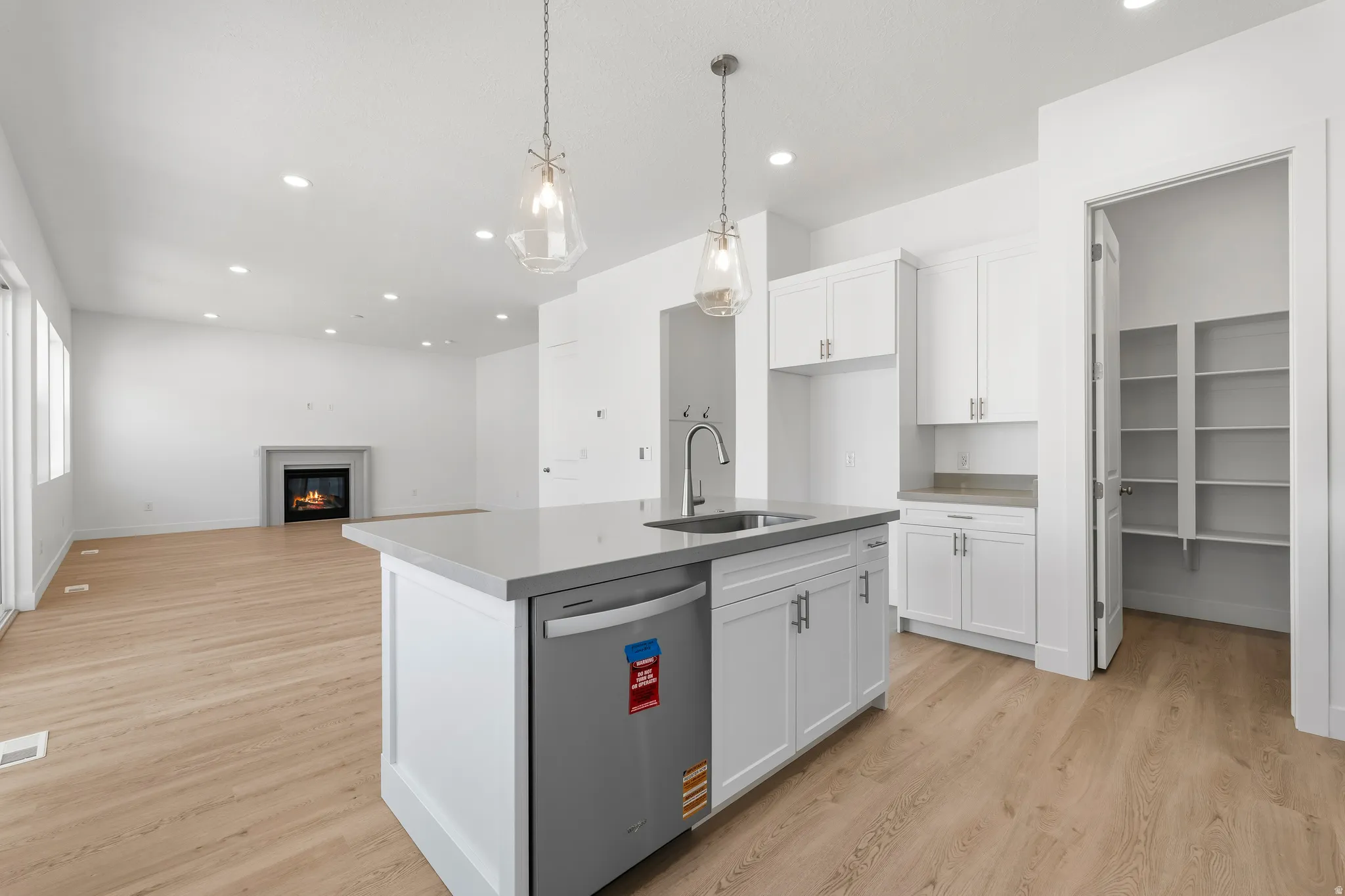 Contemporary kitchen island featuring a stainless steel undermount sink, integrated dishwasher, and pendant lighting