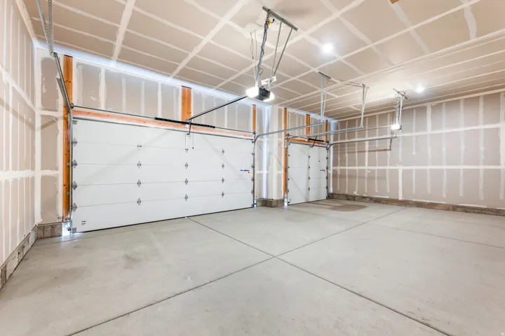 Two white sectional garage doors with exposed framing