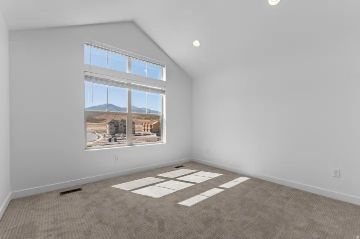 Vaulted ceiling with recessed lighting, large picture windows, and neutral carpet flooring