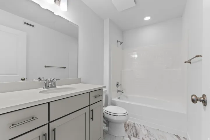 Bathroom featuring a single vanity with stone countertop, undermount sink, mirrored medicine cabinet, and a shower-over-tub combination with subway tile surround
