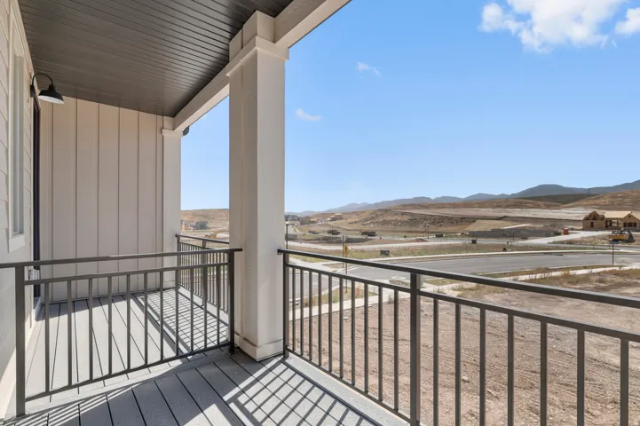 Covered balcony with composite decking, white board and batten siding, dark gray railing, and a dark gray soffit