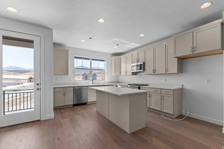 Modern kitchen featuring wood-finish flooring, recessed lighting, light-toned cabinetry, light-toned countertops, and a center island