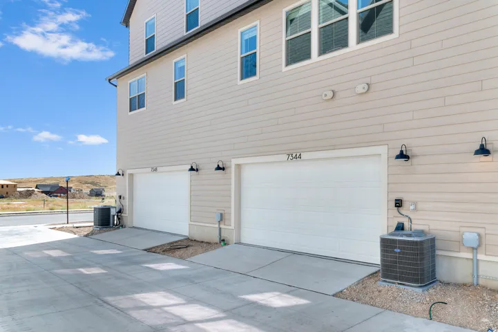 Two-car garage with individual doors, concrete driveway, and wall-mounted exterior lighting fixtures