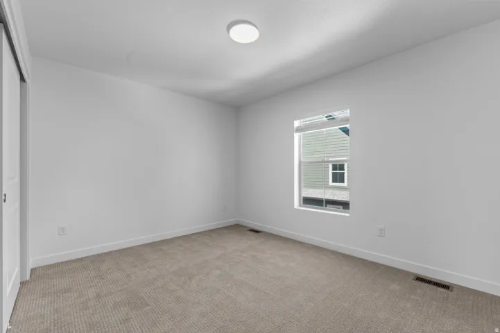 Neutral carpeting and white walls with a single window