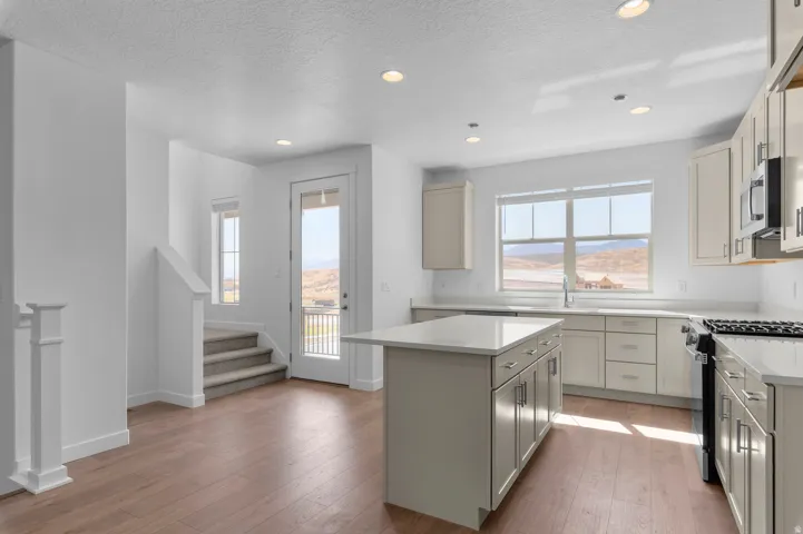 Kitchen featuring a central island with countertop, stainless steel appliances, recessed lighting, and wood-finish flooring