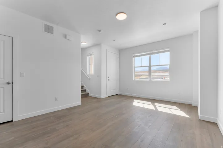 Expansive room featuring wood-finish flooring, white walls, and a large window