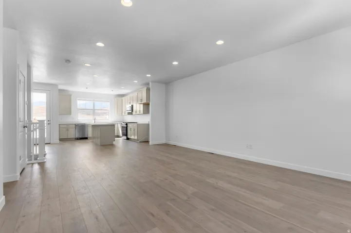 Open-concept layout featuring wood-finish flooring, recessed lighting, and a modern kitchen with a center island