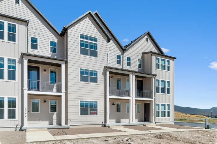 Multi-story facade featuring board and batten and shingle siding with dark trim, multiple windows, and balconies with metal railings