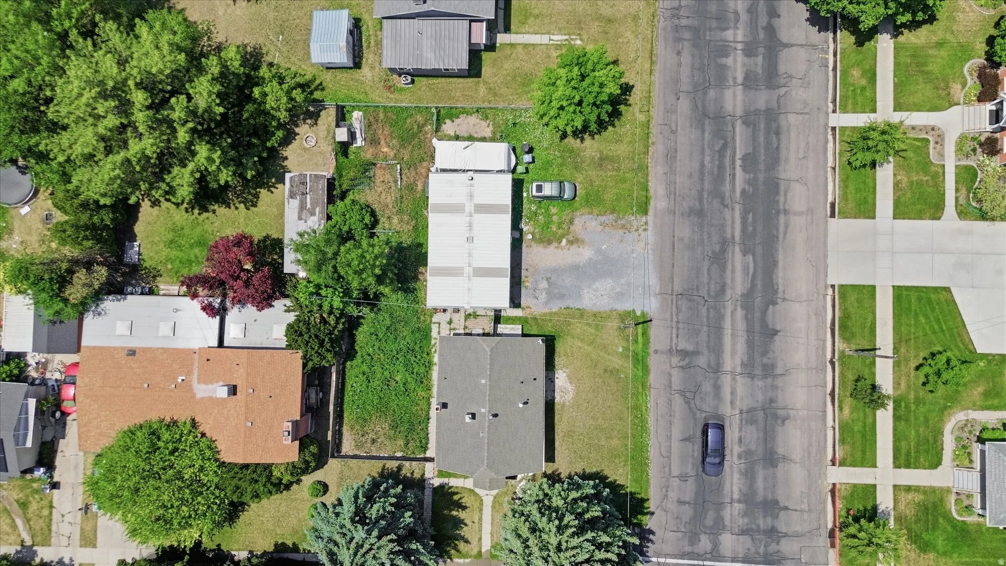 Aerial perspective showcasing a residential property with a brown-shingled roof and a spacious green yard