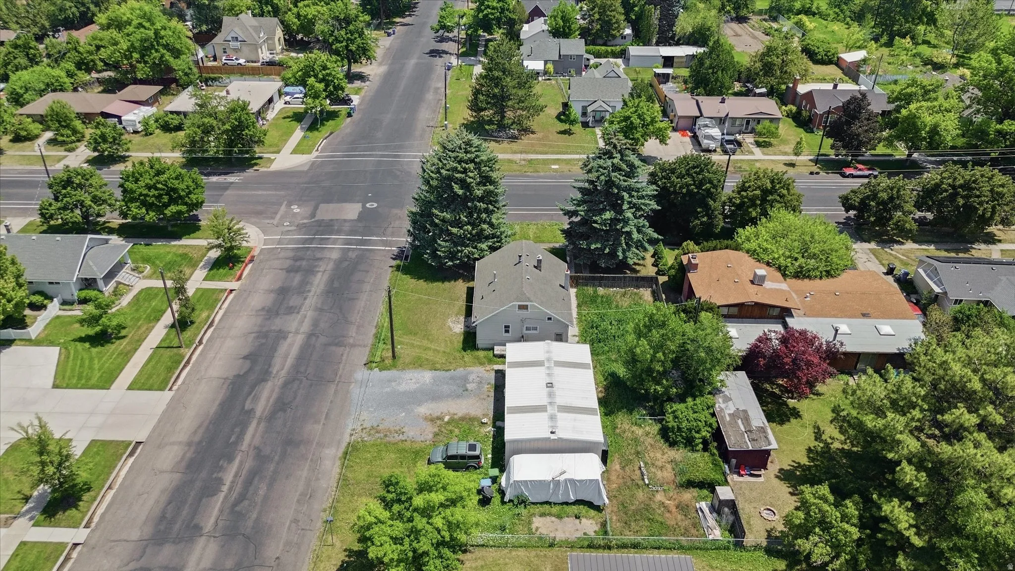 Aerial perspective showcasing a residential street with multiple properties, mature trees, and green landscaping