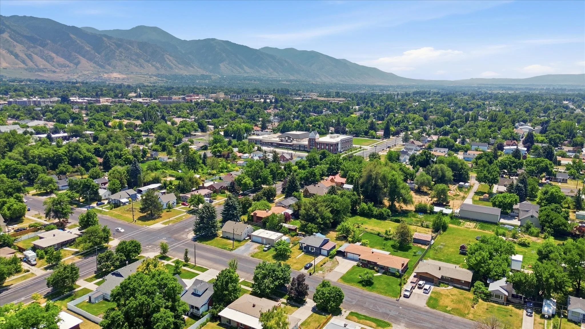 Residential area surrounded by mature trees, featuring a mountain backdrop and a clear sky