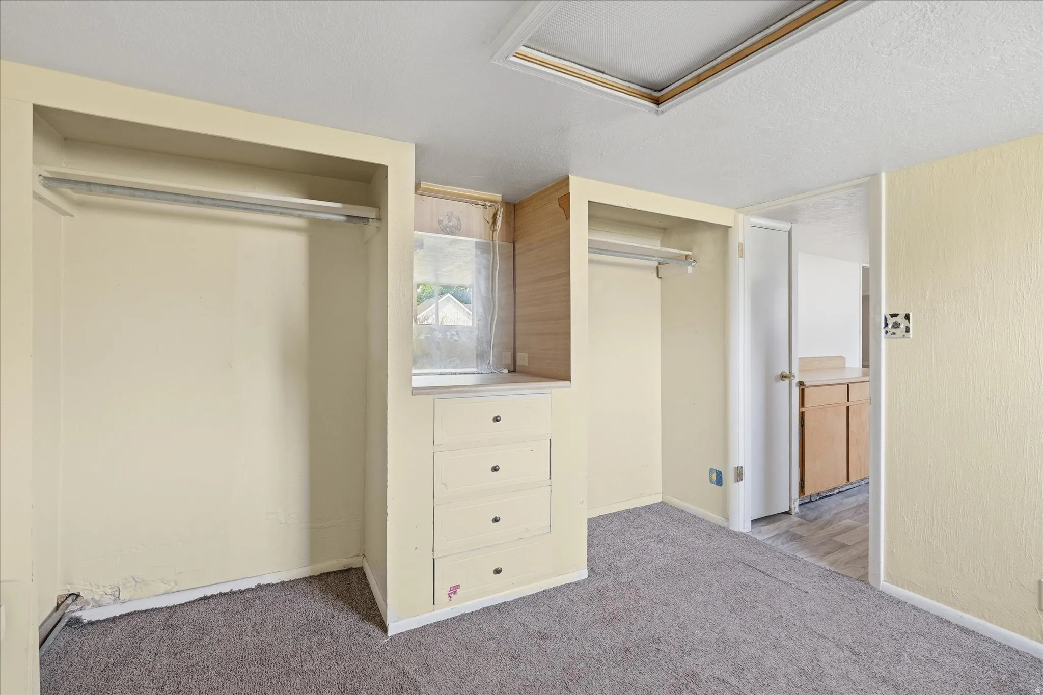 Room featuring carpet flooring, built-in open closets with hanging rods, built-in dresser with drawers, and a window