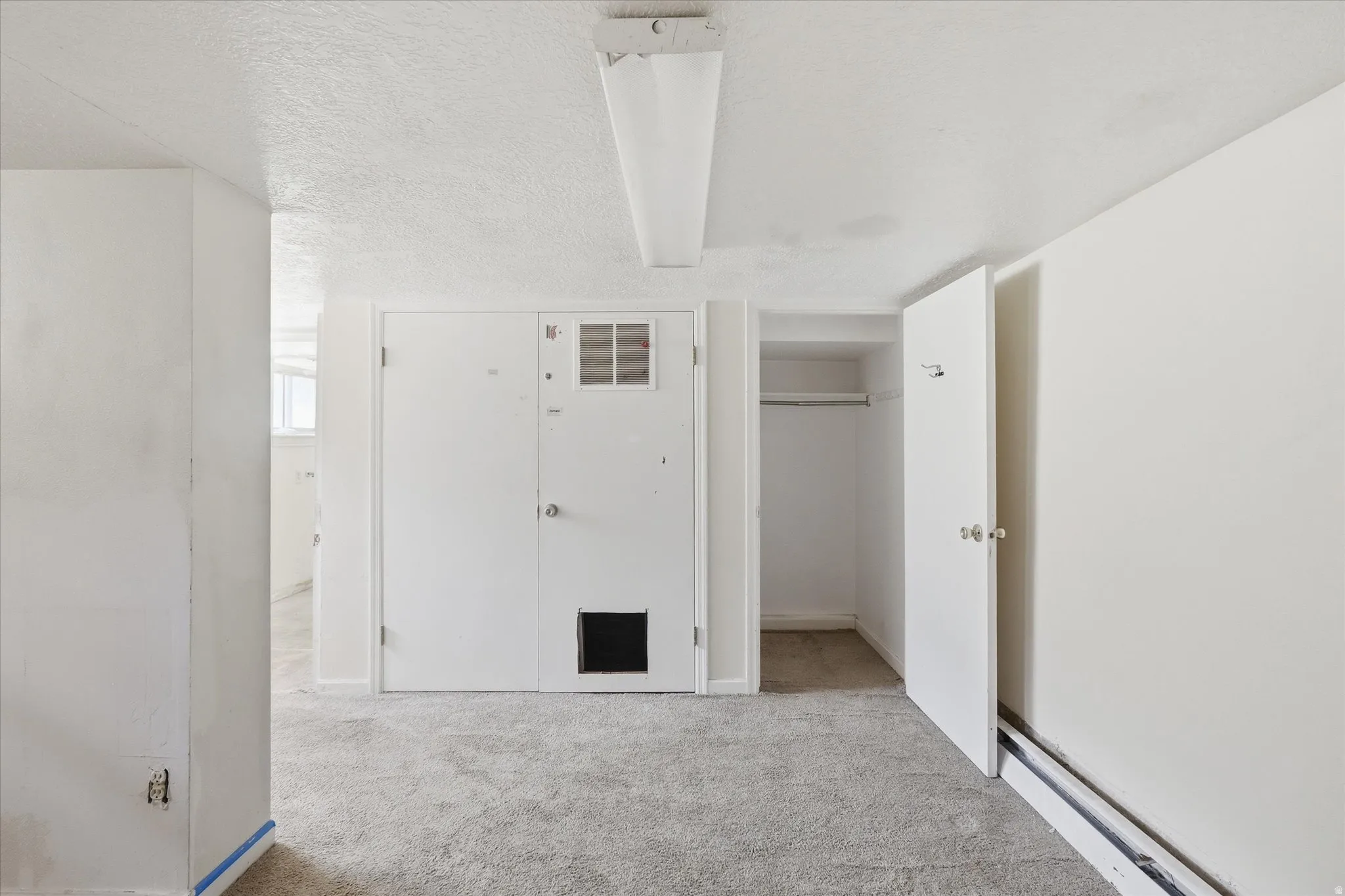 White painted walls, textured ceiling, and gray carpeted flooring