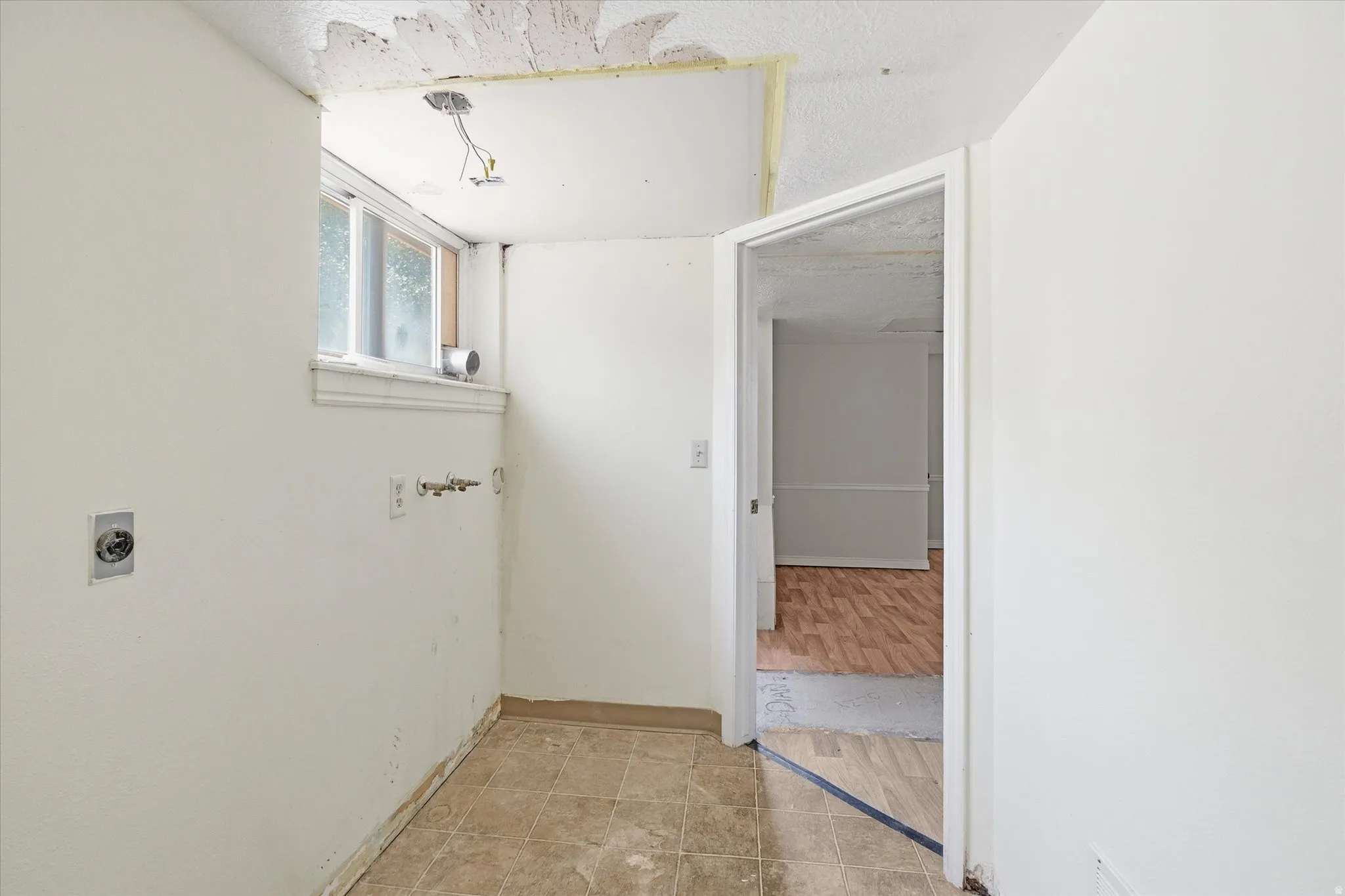Utility area featuring a window, electrical outlets, and plumbing connections for appliances