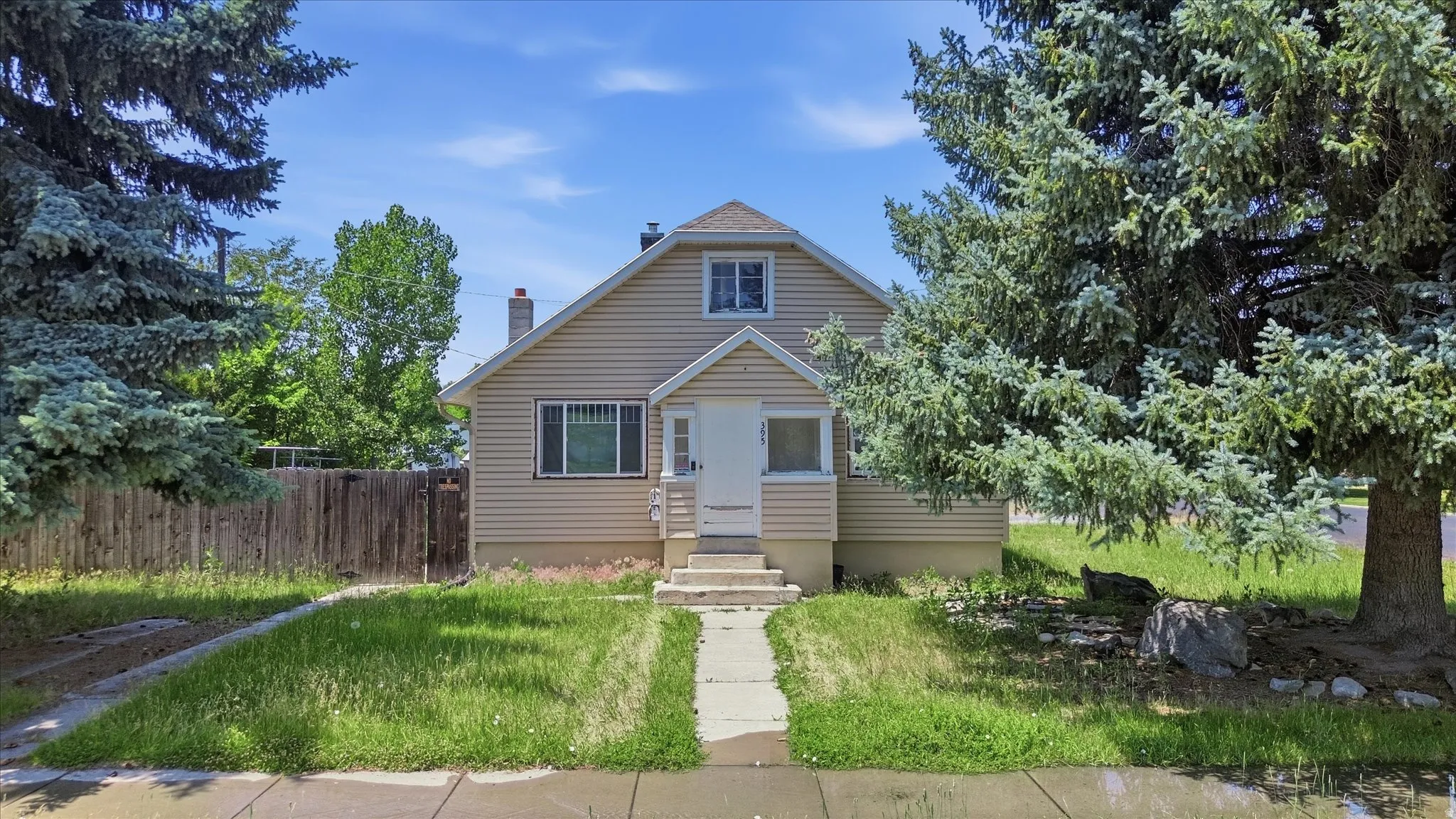 Traditional two-story residence featuring light-colored siding, a gabled roofline, and an enclosed front porch