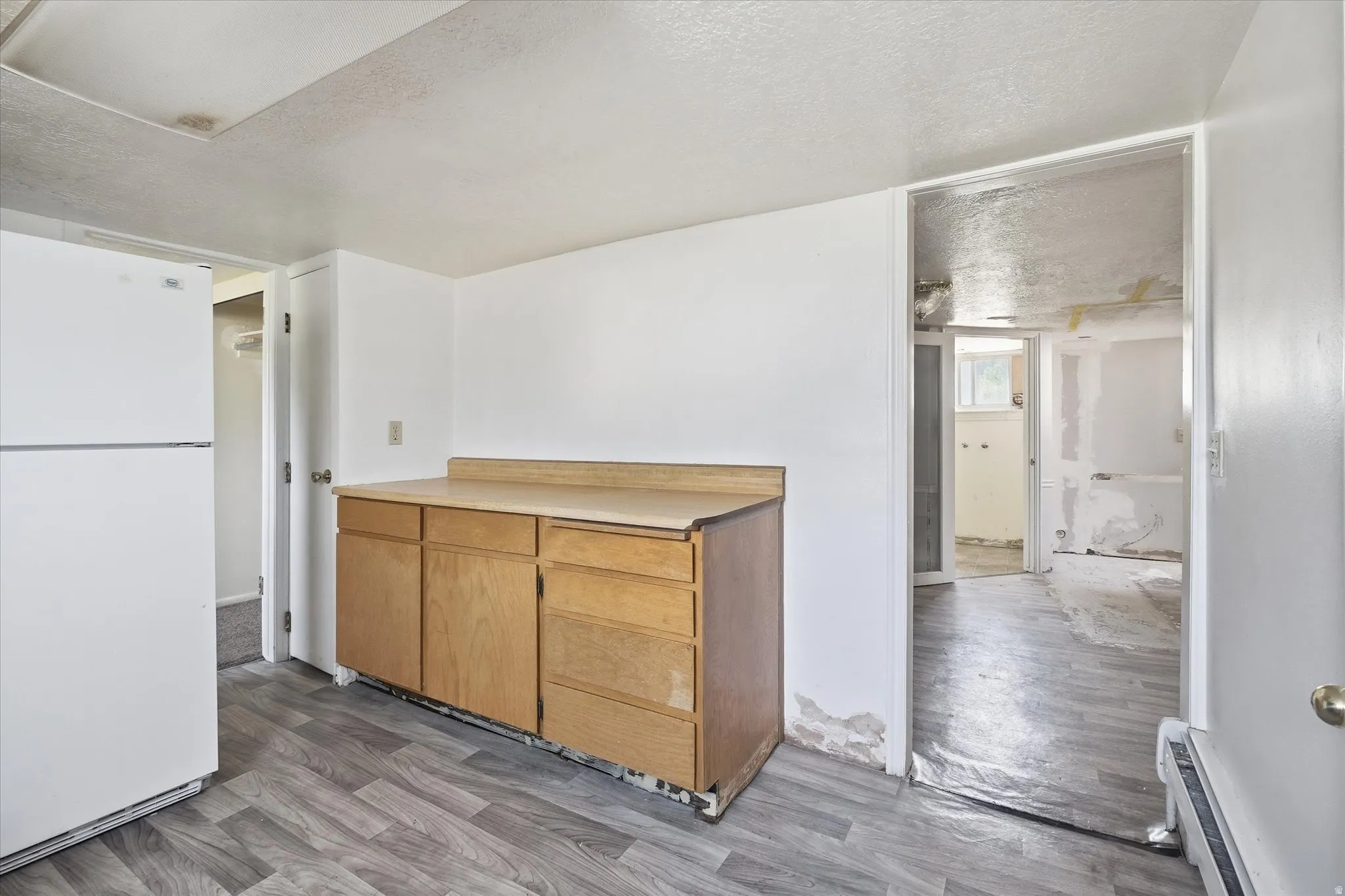 White refrigerator, wood-finish base cabinetry, and light wood-finish countertop
