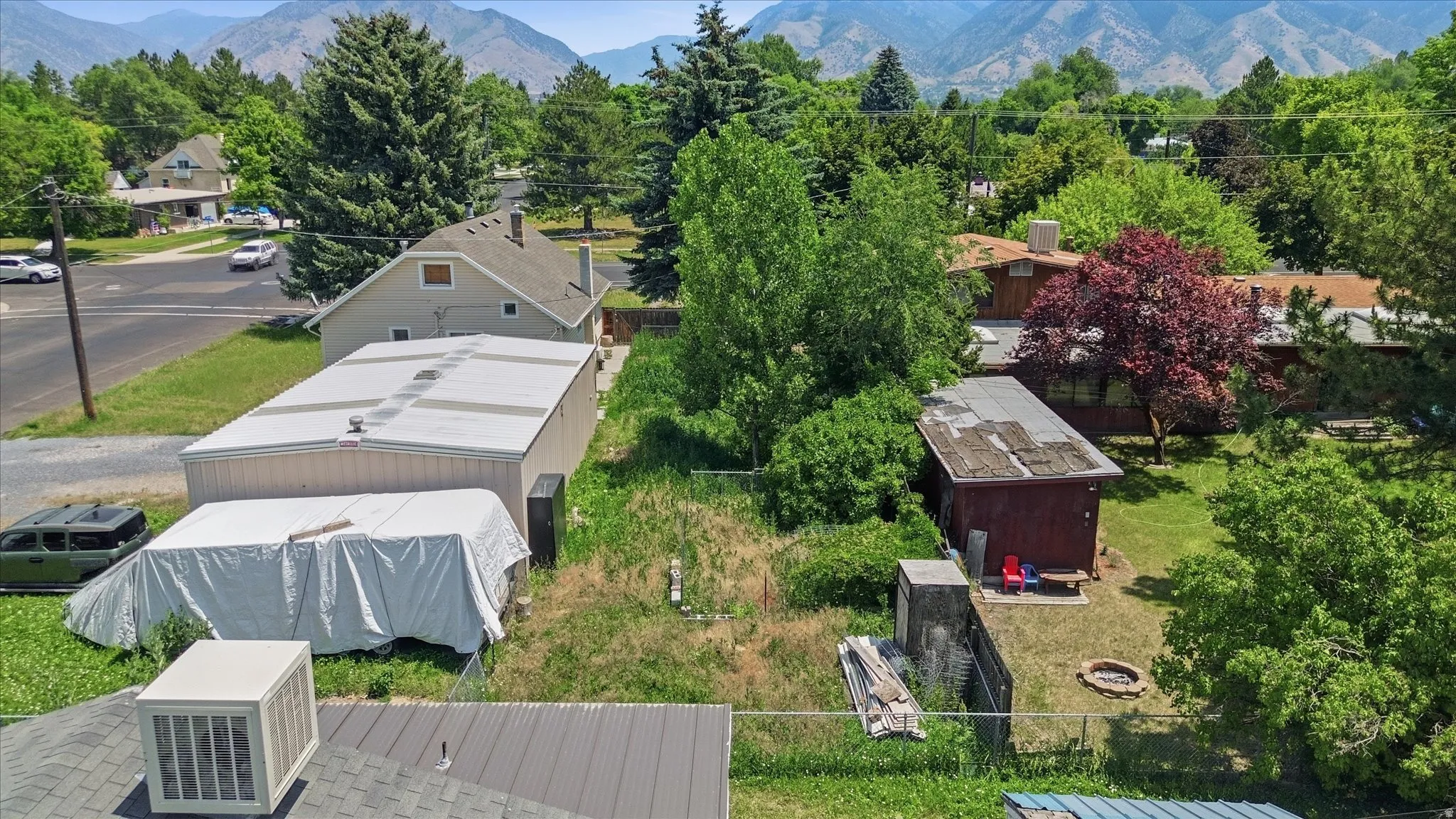 Expansive property featuring multiple structures, including a long detached garage with a metal roof, and a separate red-sided outbuilding