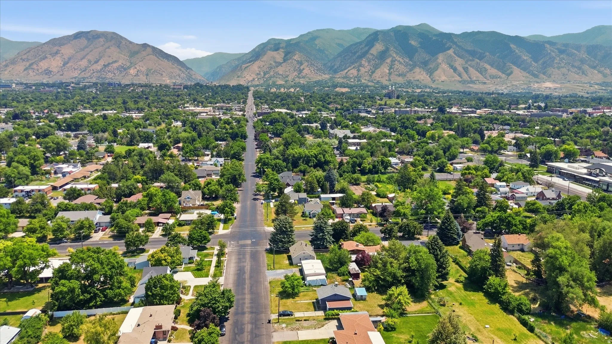 Expansive residential area featuring a broad boulevard, abundant mature trees, and a distant mountainous backdrop