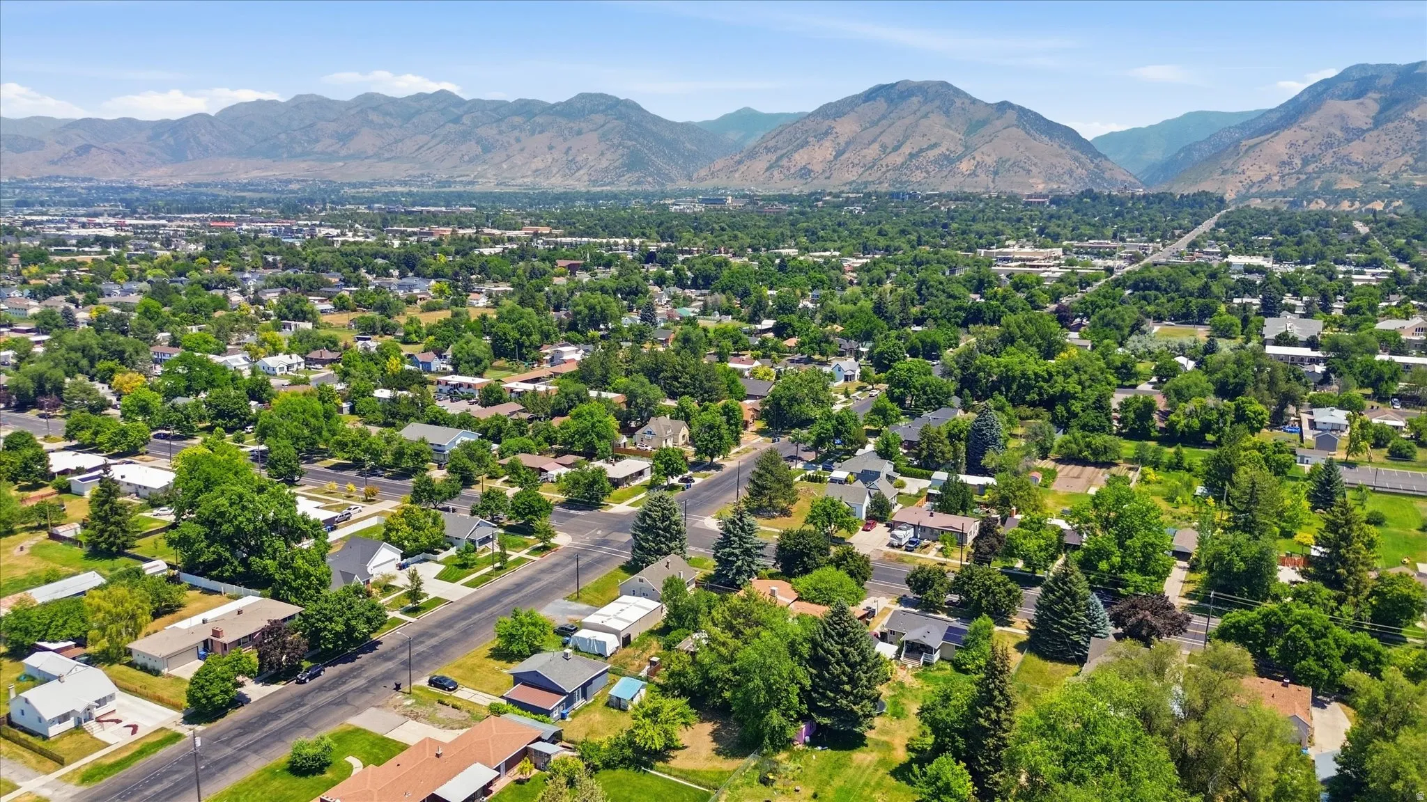 Expansive residential area featuring established homes, mature trees, and paved streets, framed by distant mountains