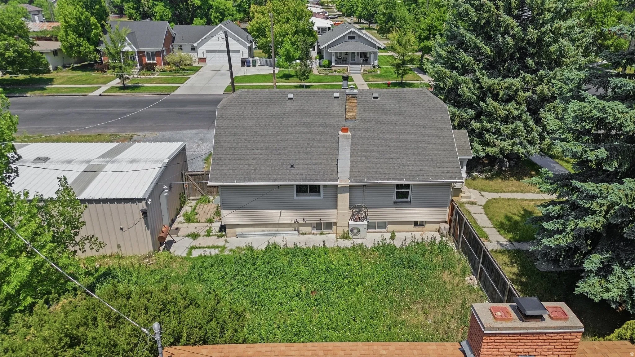 Gable roofline with asphalt shingles and a central brick chimney
