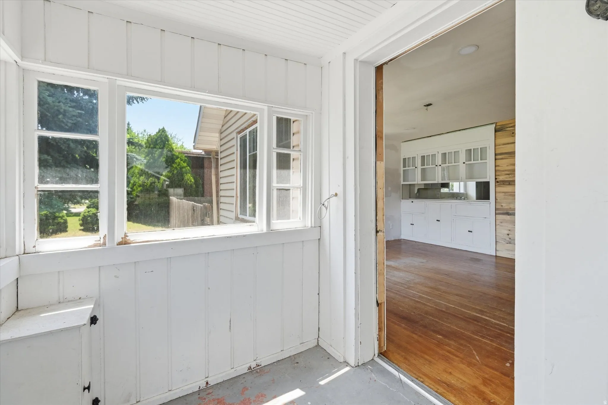 Enclosed porch featuring multiple windows and a built-in storage bench