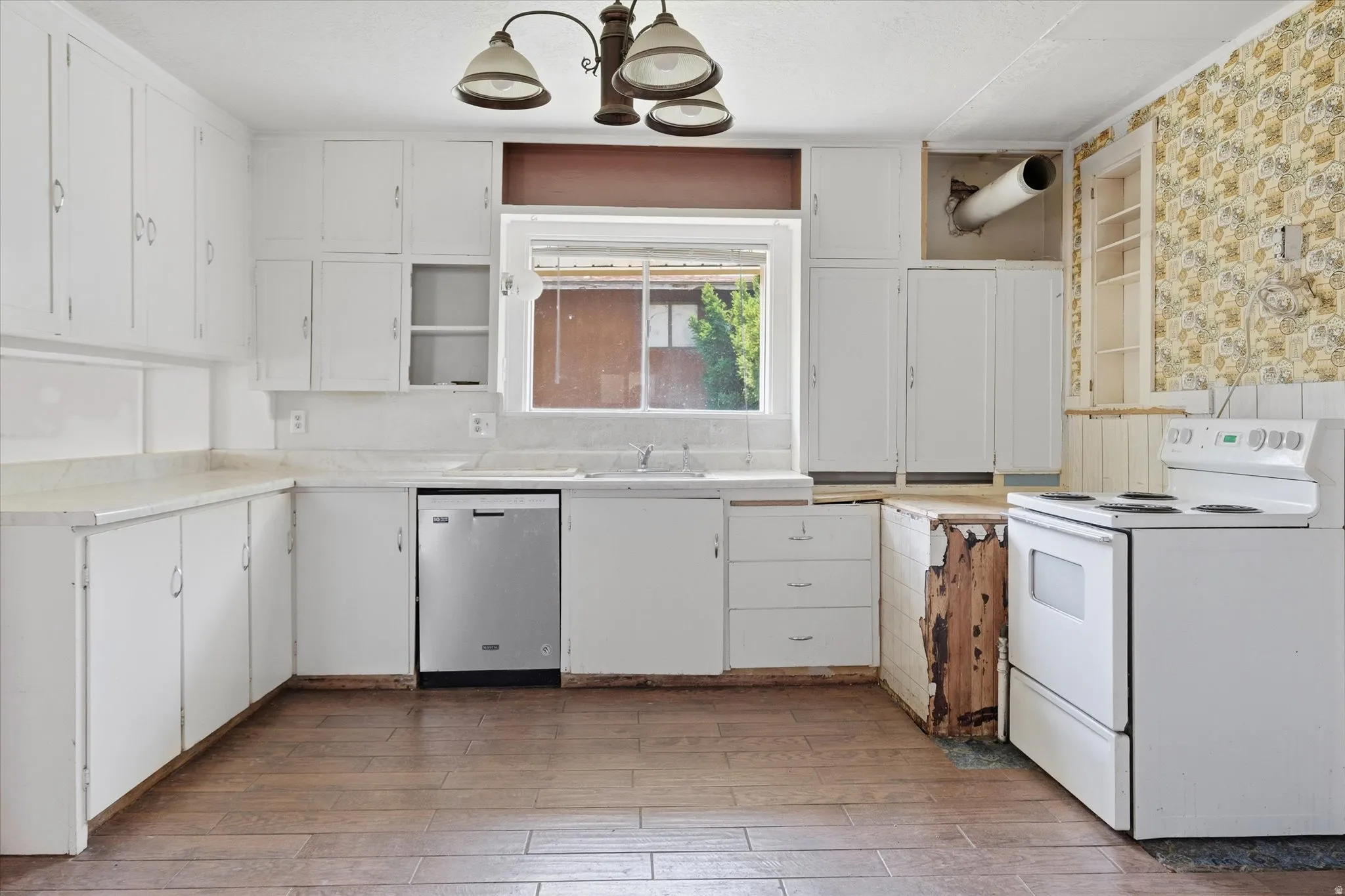 Kitchen featuring white cabinetry, wood-finish flooring, a stainless steel dishwasher, a white electric range, and a window above the sink