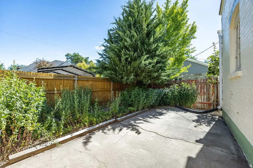 Concrete patio area featuring a perimeter fence and mature landscaping