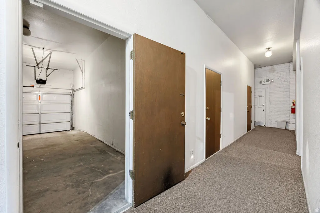 Interior hallway with textured carpet flooring, leading to multiple wood-panel doors