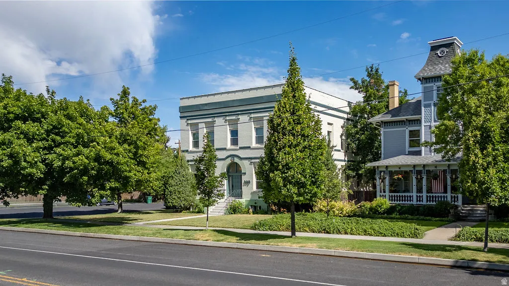 Historic-style building featuring a light green facade with white trim, arched entryway, and multiple windows