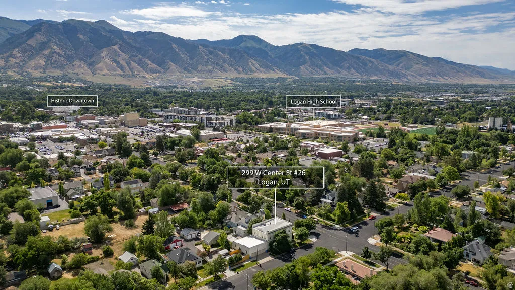 Aerial perspective showcasing a residential area with varied architecture, mature trees, and mountainous terrain