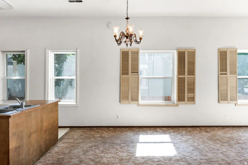 Open-concept living area with a built-in wood-finish breakfast bar, multiple windows, and a decorative chandelier