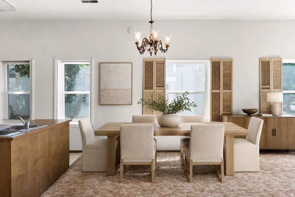 Spacious dining area featuring a chandelier, light wood-finish dining table, and upholstered chairs