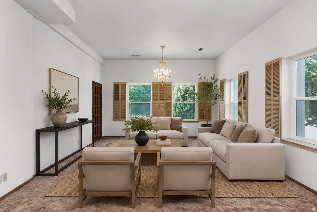Bright living area featuring multiple windows with wood shutters, a decorative chandelier, and a dark wood entry door