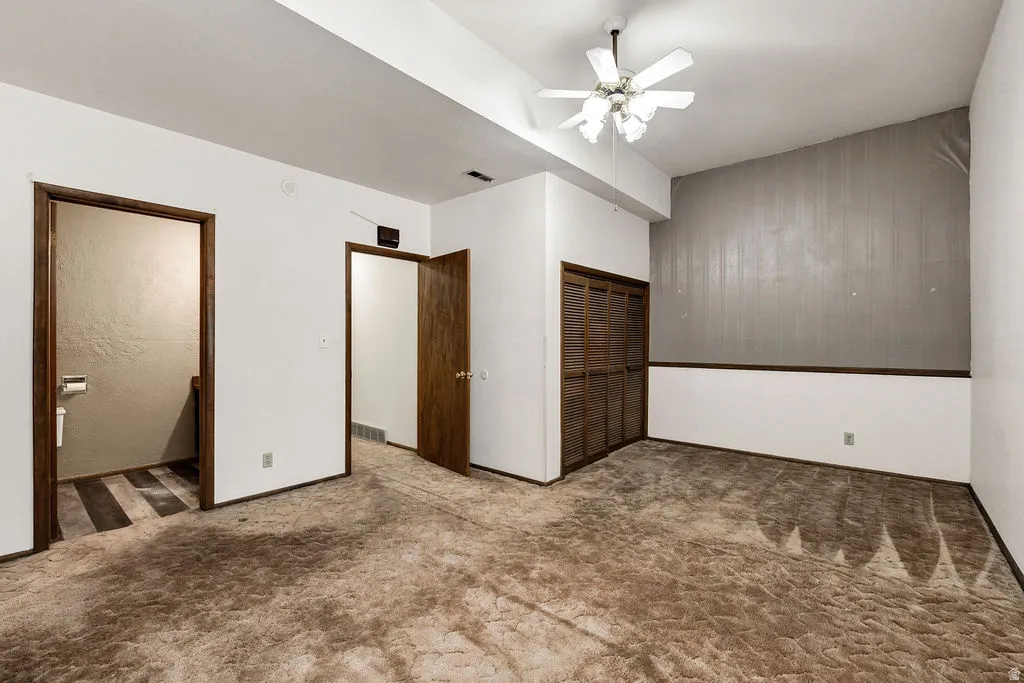 Room featuring a slatted bi-fold closet, ceiling fan, and two interior doorways