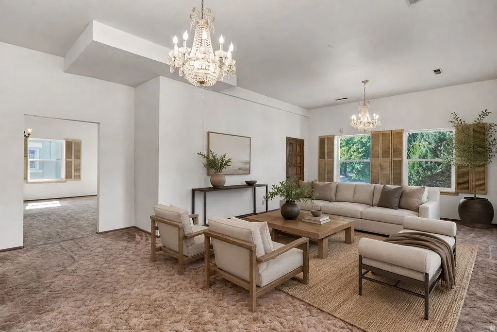 Spacious interior featuring a crystal chandelier, multiple windows with natural wood shutters, and an additional crystal chandelier in the far room