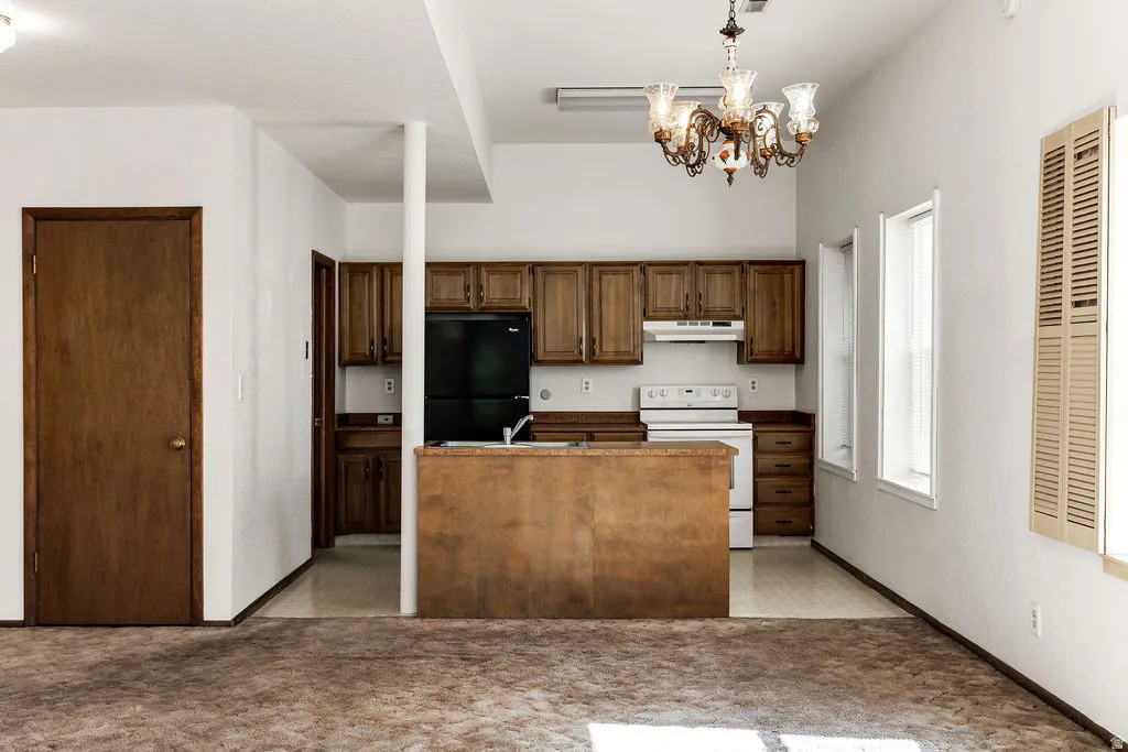 Kitchen area featuring wood-finish cabinetry, a white range, and a black refrigerator