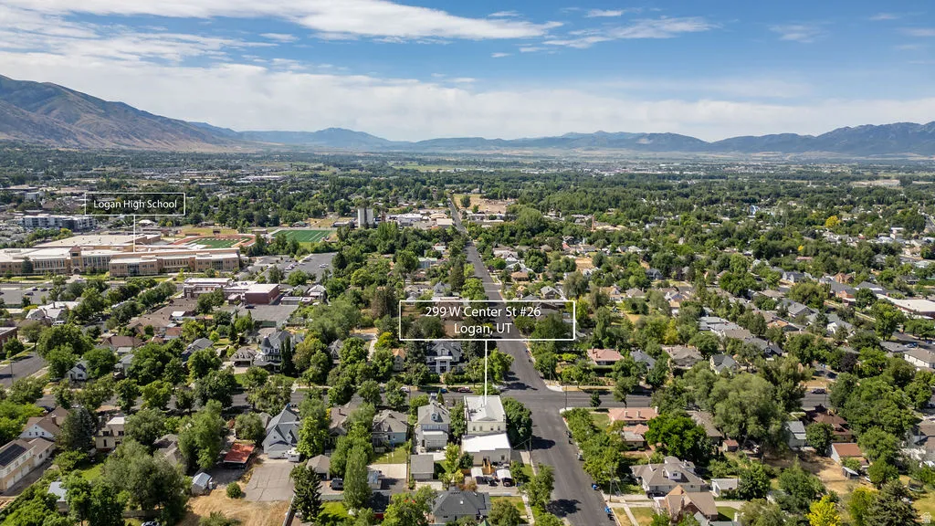 Aerial perspective showcasing a residential and commercial area with abundant mature trees, mountain ranges in the distance, and prominent buildings